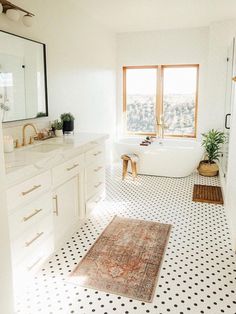 a white bathroom with black and white tile flooring, sink, bathtub and large window