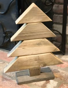 a small wooden christmas tree sitting on top of a wood block in front of a fireplace