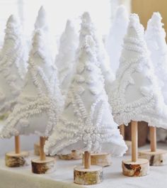 small white christmas trees are lined up on a table with wood slices in front of them