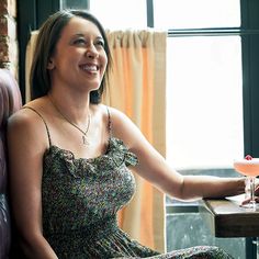 a woman sitting at a table with a drink in her hand