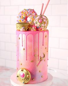 a pink and gold birthday cake with sprinkles, donuts, and other decorations