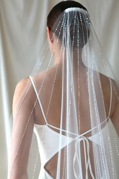 the back of a woman wearing a wedding veil with beads on it's side