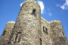 an old stone building with two windows on the top and one at the bottom, against a blue sky