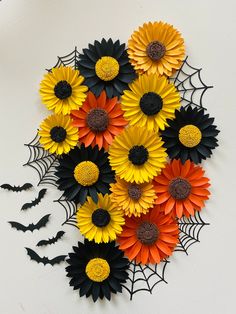 a bunch of fake sunflowers and spider web on a white wall with bats