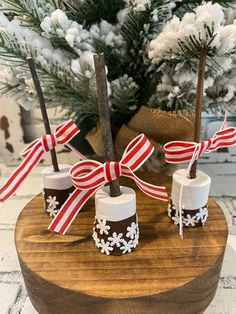 three christmas candles with red and white bows on them are sitting on a wooden stand