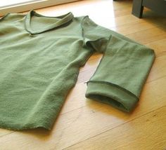 a green shirt laying on top of a wooden floor