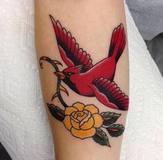 a red bird and yellow rose tattoo on the arm