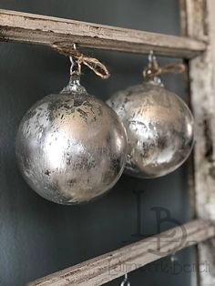 two silver ornaments hanging from a wooden shelf