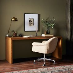 a desk with a chair, lamp and pictures on the wall in front of it