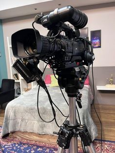 a camera set up on a tripod in front of a bed with a blue wall