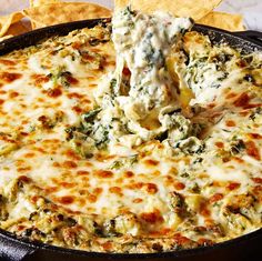 a tortilla dish with spinach and cheese being scooped from the skillet