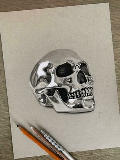 a drawing of a skull on paper next to a pencil