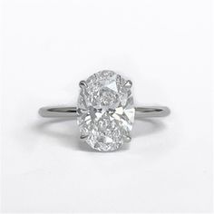 an oval cut diamond ring on a white background