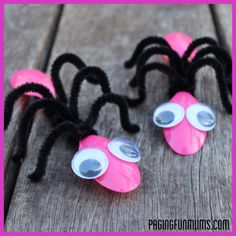 two pink plastic playdoughs with googly eyes on them sitting on a wooden table