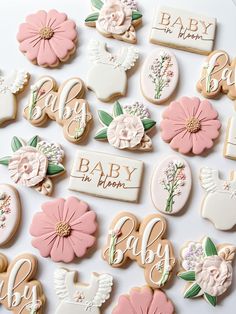 baby shower cookies are laid out on a white surface with pink and green flowers in the middle