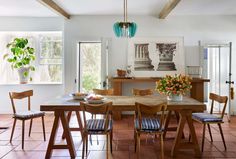 a dining room table with four chairs and a potted plant in the center on top