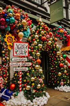 christmas decorations are on display in front of a building with large trees and street signs