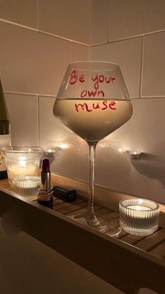 a wine glass sitting on top of a wooden shelf next to a bottle and glasses