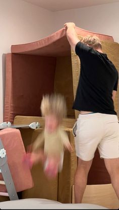 a man and child are playing in a room with bunk beds, pink furniture and other items