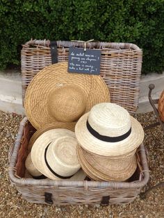 several straw hats in a wicker basket with a chalkboard sign on the side