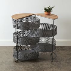 a round table with four metal baskets on it and a potted plant in the corner