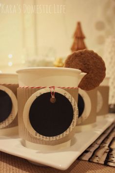 there are three coffee cups with measuring tape around them on a plate next to cookies