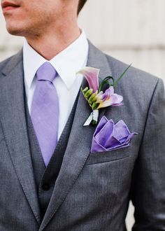 a man in a gray suit with a purple flower on his lapel