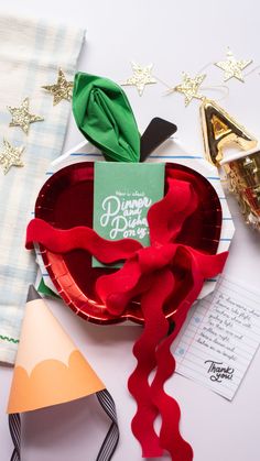 an apple shaped paper plate sitting on top of a table next to a party hat