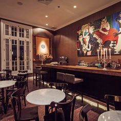 an empty restaurant with tables and chairs in front of a painting on the back wall