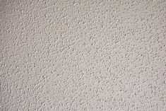 a white wall that has some small dots on the surface and is very rough looking