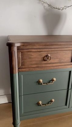 an old dresser has been painted green and brown with gold knobs on the drawers