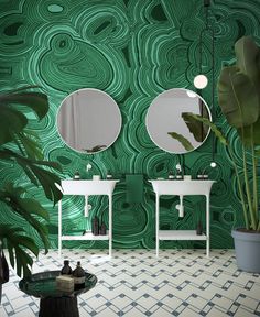 a bathroom with two sinks and mirrors in front of a green wallpapered background