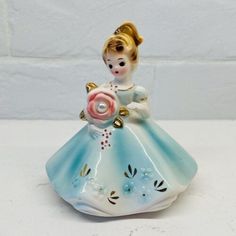 a ceramic figurine with a flower in her hand