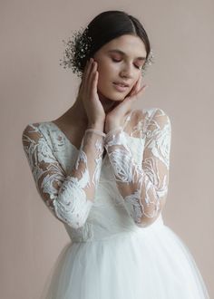 a woman in a white dress holding her hand to her face