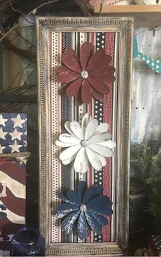 an old frame with flowers on it in front of some american flags and other patriotic decorations