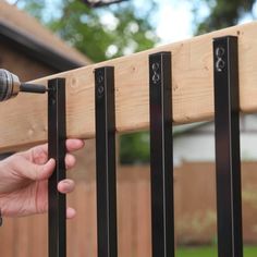 a person holding a microphone up to a wooden fence with black metal bars on it