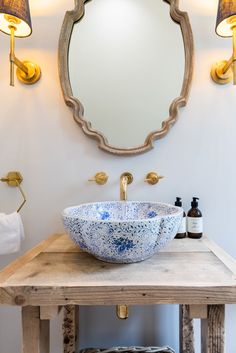 a blue and white bowl sink sitting on top of a wooden table next to a mirror