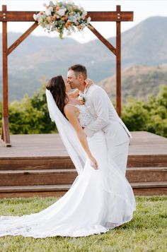 a bride and groom kissing in front of a gazebo