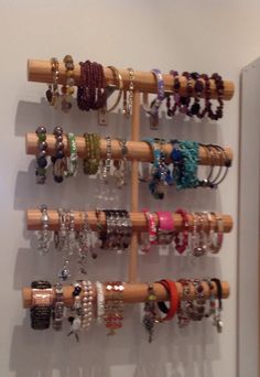 a rack with bracelets and rings hanging from it's sides on a wall