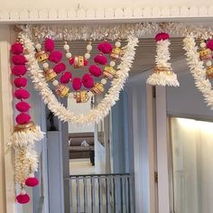 a hallway decorated with pink and white pom poms, hanging from the ceiling