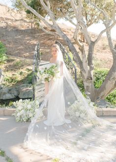 a woman in a wedding dress is holding a bouquet and posing for the camera with her veil over her head