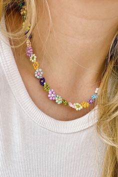 a woman wearing a multicolored beaded necklace with flowers on the front and back