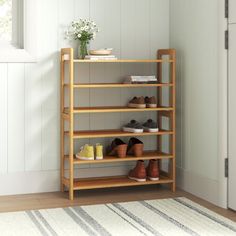 a wooden shoe rack with shoes on it in a white room next to a door