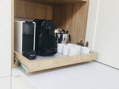 there is a coffee maker and cups on the shelf in the kitchen cupboards,