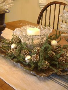 a dining room table decorated for christmas with pine cones and candles