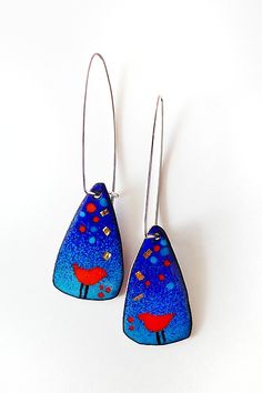 pair of earrings with blue and red designs on them, hanging from silver ear wires