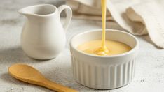 a small white bowl filled with liquid and a wooden spoon next to it on a table