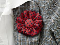 a close up of a suit with a red flower on it's lapel