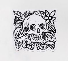 a sticker with a skull and flowers on it's side, in black ink