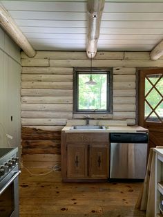 a kitchen with wooden walls and flooring next to a stove top oven under a window